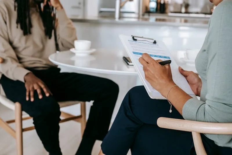 Woman in a CBT session with her therapist, working on the thought patterns behind impostor syndrome in a calm, professional setting