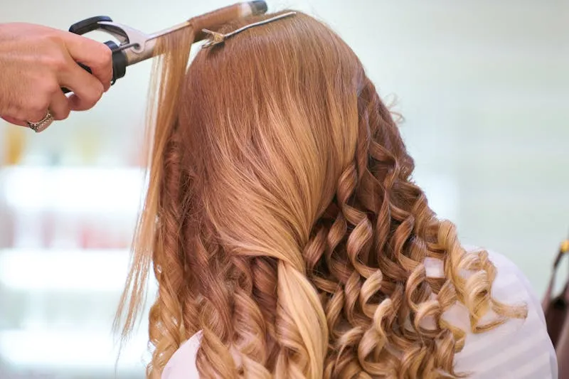 Wedding morning hair and makeup session — several women being prepared in a bright room, dresses hanging in the background