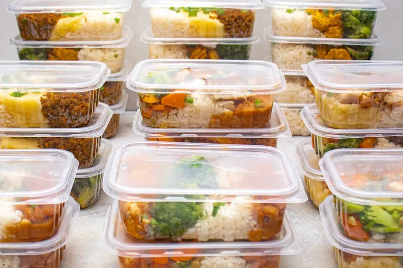 Stacked meal-prep containers with rice, stew and vegetables