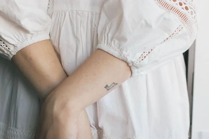 Puffed white cotton sleeves with embroidered inserts, arms crossed