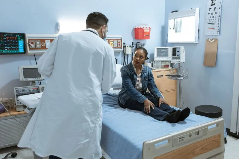 Woman sitting on an exam table talking with a doctor