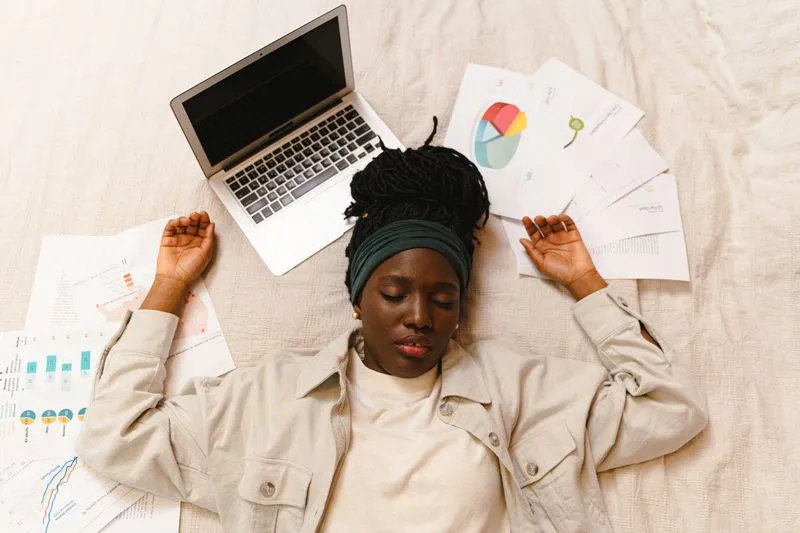 Exhausted woman lying down, surrounded by work papers