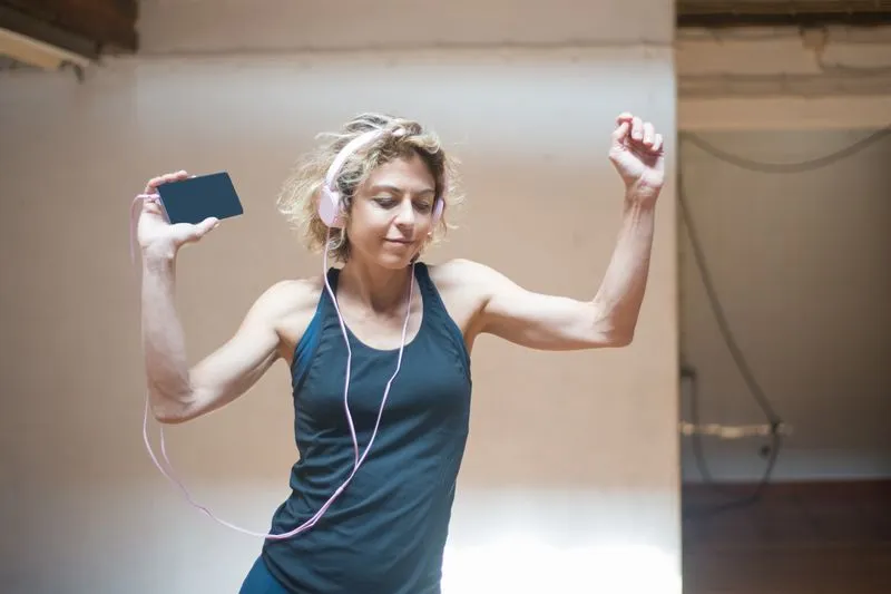 Woman dancing with headphones on and phone in hand