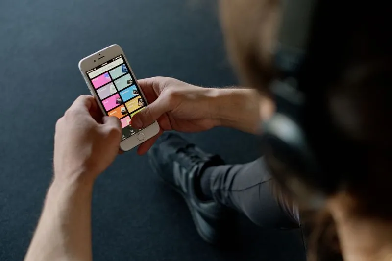 Person wearing headphones checking a playlist app on their phone