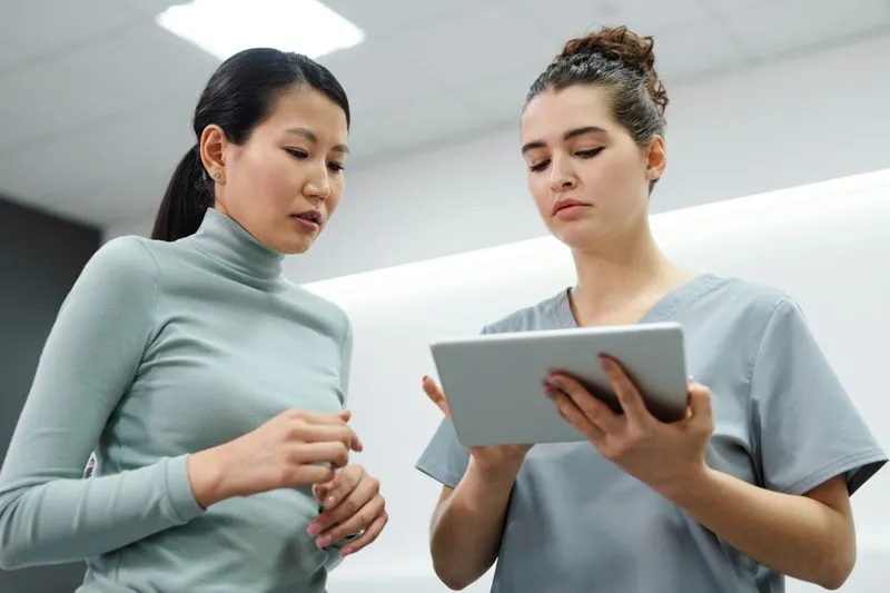 Clinician in scrubs showing a tablet screen to a female patient