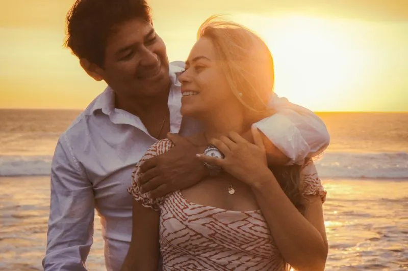 Smiling couple embracing on a beach at golden-hour sunset