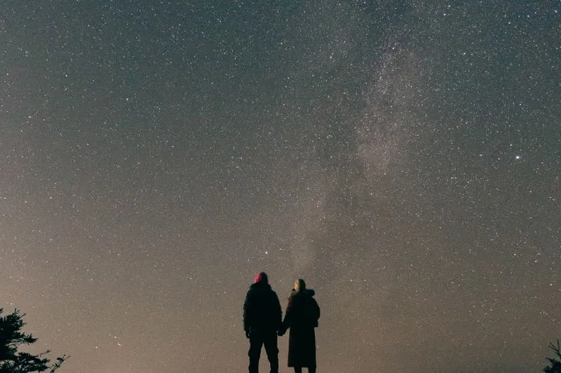 Silhouette of a couple holding hands under a starry sky with the Milky Way