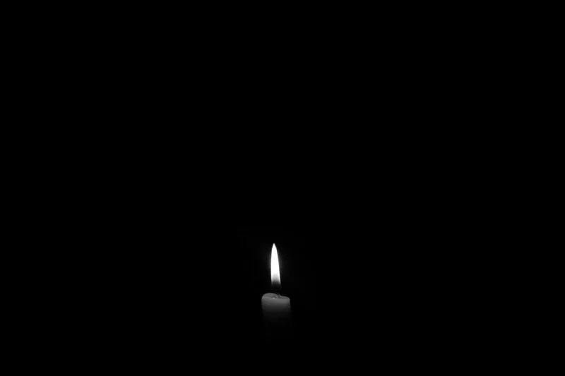 A lit candle flame glowing in the dark, symbolising fire, one of the four astrological elements