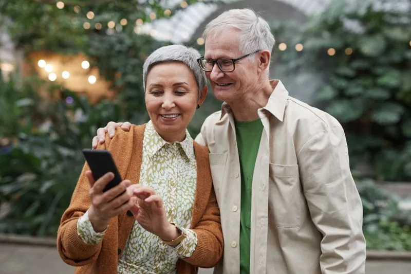 Smiling couple looking together at a smartphone screen in a glasshouse