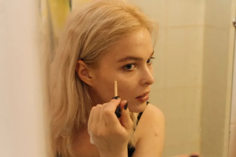 Careful make-up application in front of a bathroom mirror, an everyday gesture