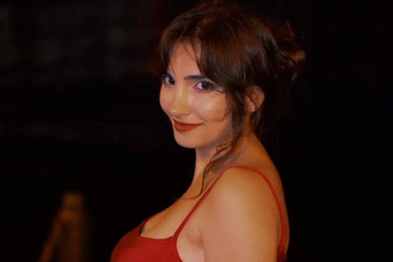 Portrait of a woman with brick-red lipstick in a red top against a dark evening backdrop
