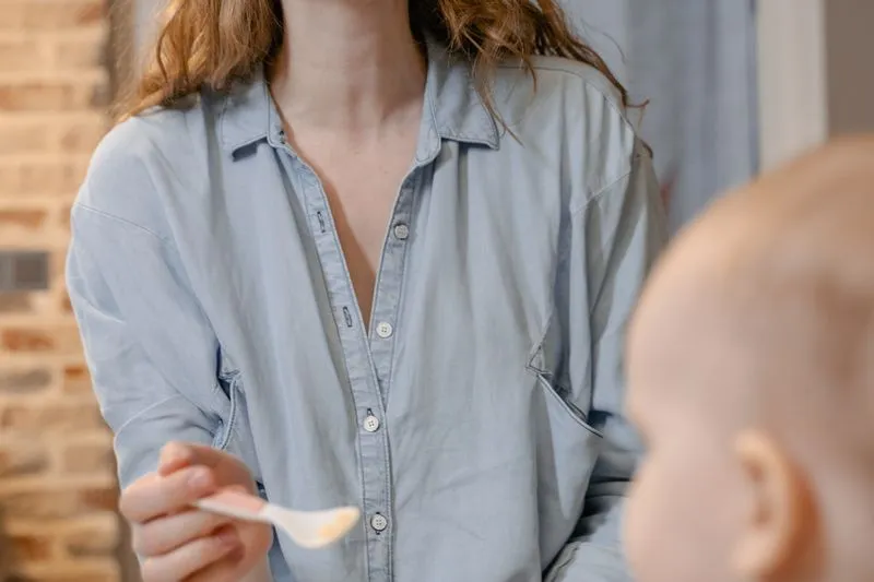 A mother holding out a small spoon to her baby