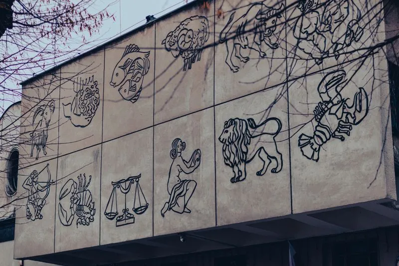 The twelve signs of the zodiac carved in relief on a building façade, seen through bare branches