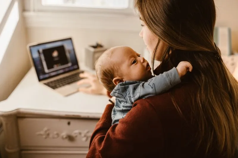 Mother working on her laptop while holding her baby