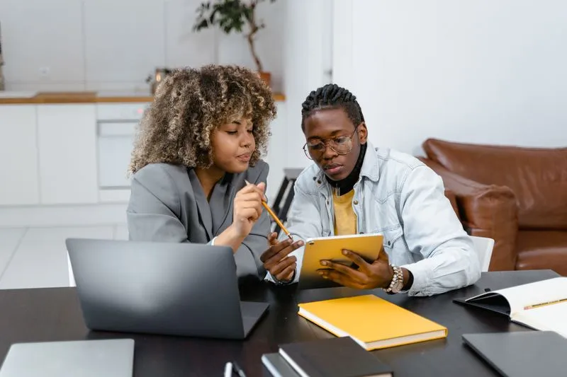 Couple looking at a tablet and notebooks to organise how they split tasks