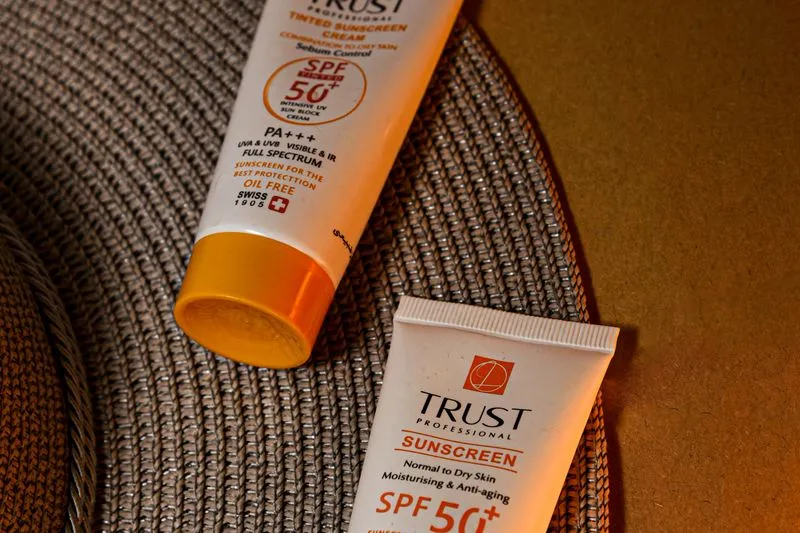 Two SPF50+ sunscreen tubes lying side by side on a woven placemat
