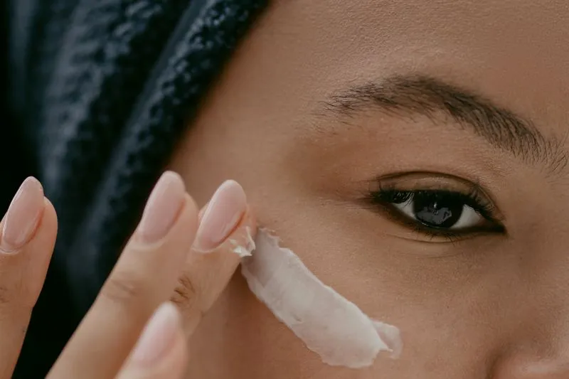 Close-up of a woman smoothing sunscreen under her eye with her fingertip