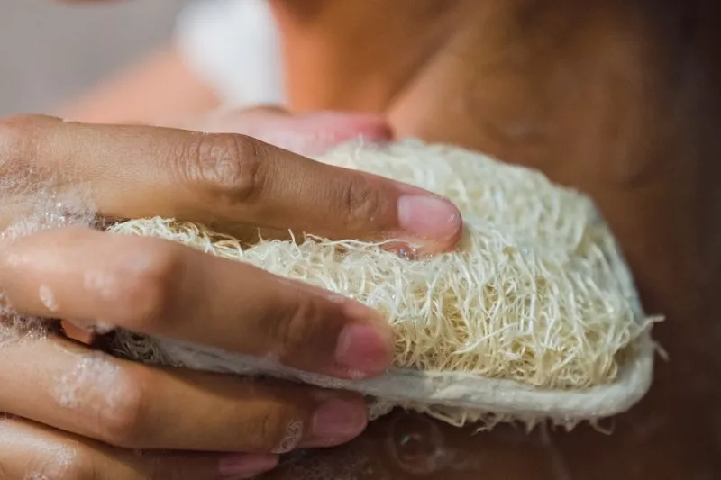 Soapy hands rubbing a loofah sponge on the skin