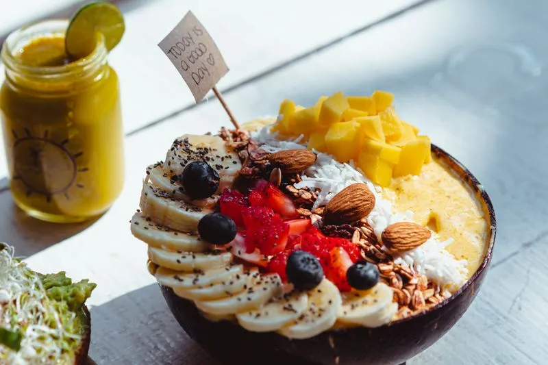 Colourful smoothie bowl with mango, banana and berries, topped with almonds and coconut