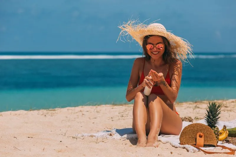 Woman applying sun cream on the beach in summer