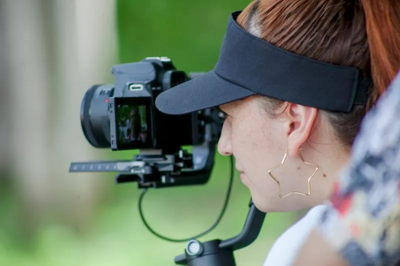 Woman in a visor filming outdoors with a camera on a handheld stabiliser
