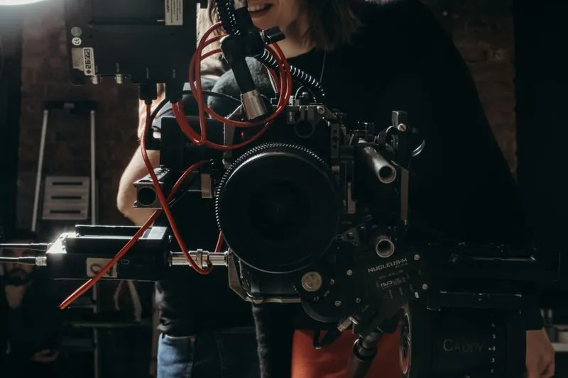 Smiling woman behind a cinema camera on a film set