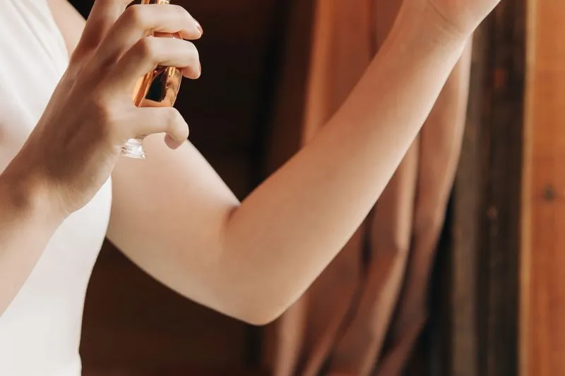Woman spraying perfume on the inside of her forearm