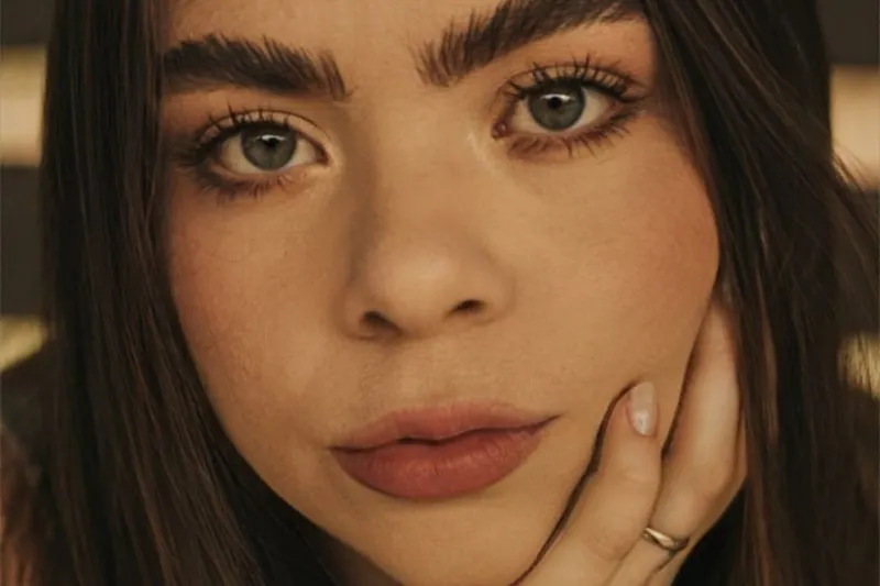 Close-up of a woman with glowing skin, full brows and matte nude lips