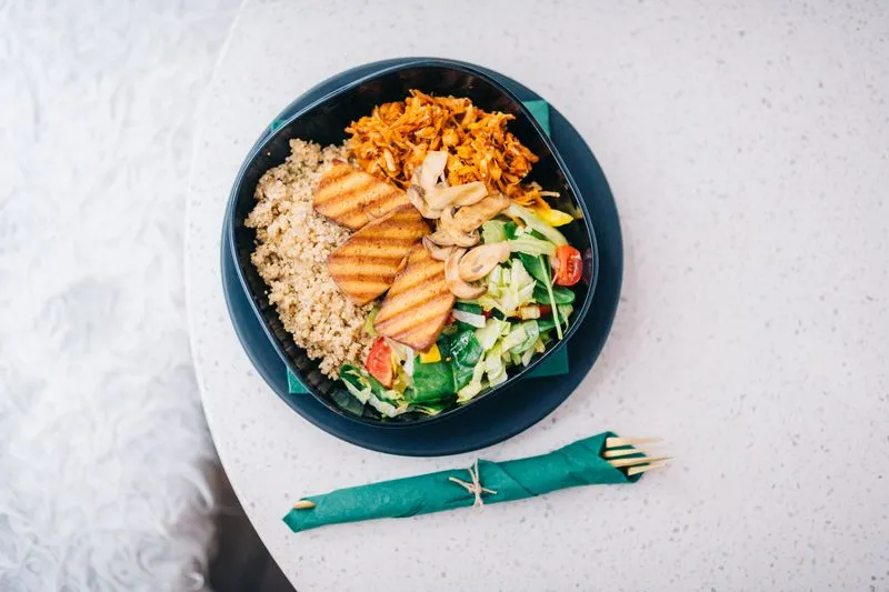 Overhead view of a bowl of quinoa, grilled tofu, mushrooms and raw vegetables
