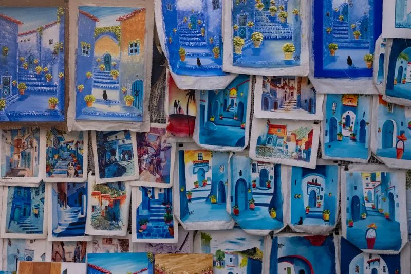 Stalls of hand-painted blue artwork depicting Chefchaouen's streets, Morocco