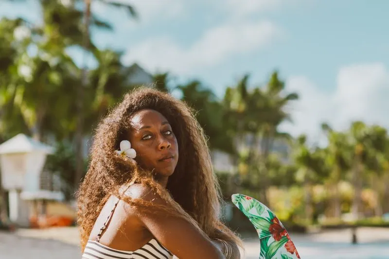 Woman with a white flower in her hair on a tropical beach lined with palm trees
