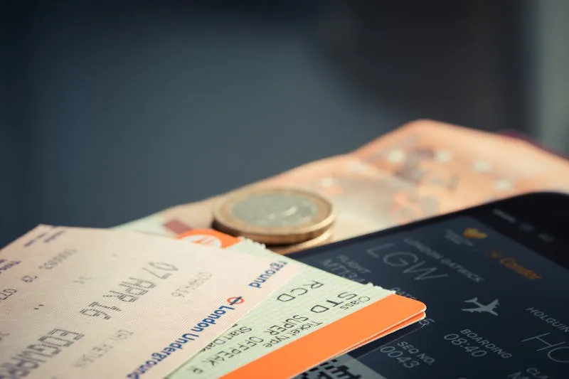 Train tickets, a coin and a phone showing a boarding pass