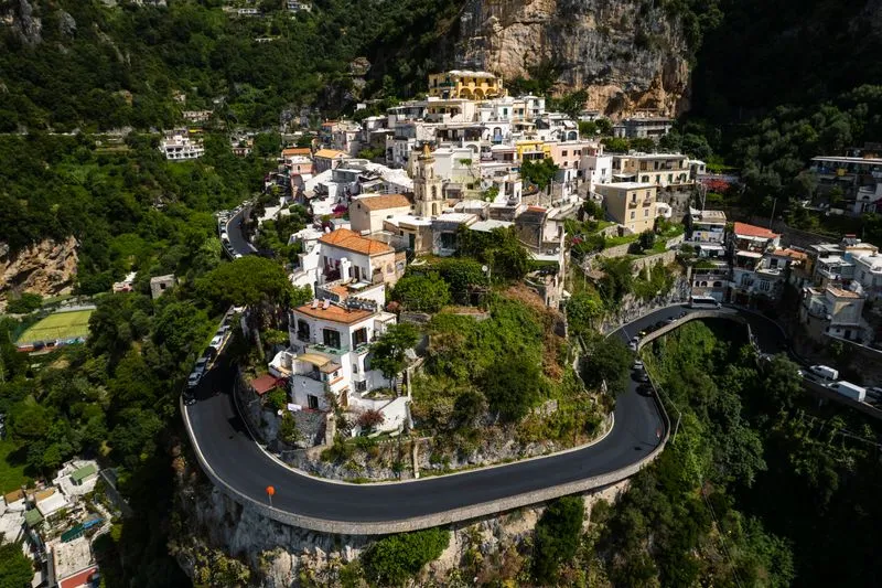 Aerial view of the Amalfi Coast road hairpinning around a cliffside village