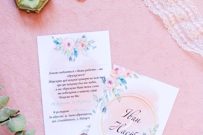Two watercolour floral invitations written in Ukrainian on a pink background, showing the date and the restaurant address