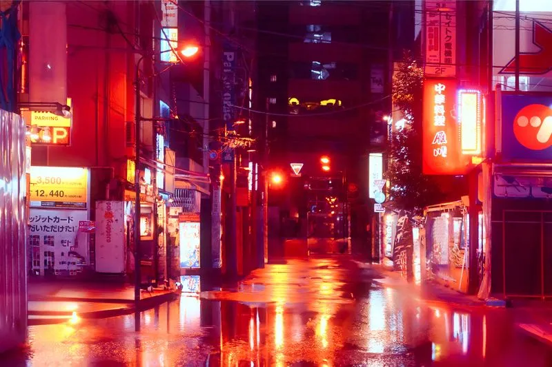 Empty rain-soaked street at night, bathed in the red glow of neon signs