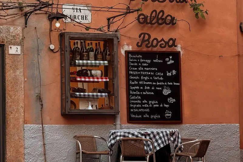 Chalkboard menu on the wall of an Italian osteria, above a table with a checked tablecloth