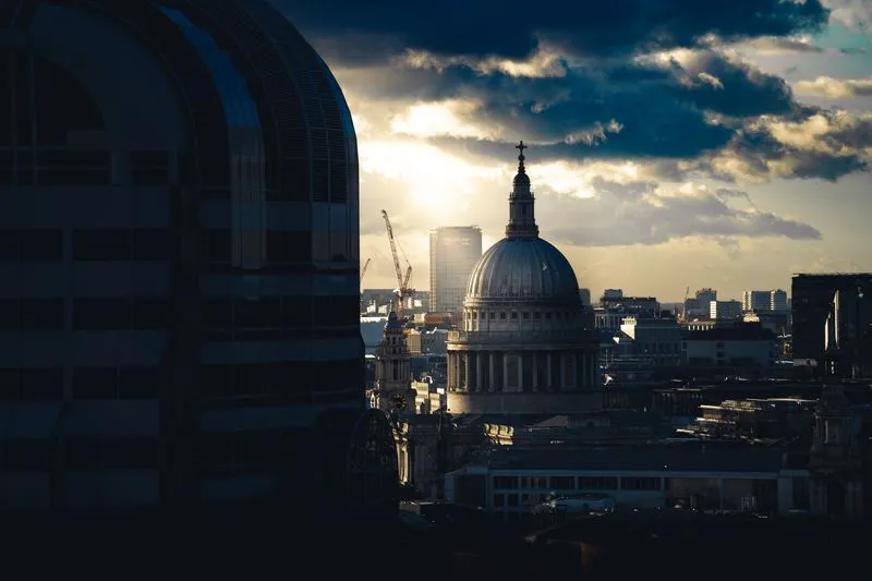 Dome of St Paul's Cathedral in silhouette against a low Sun breaking through the clouds over London