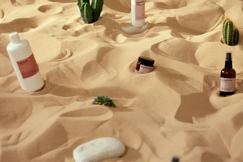 Bottles of sun cream and sun lotion stuck in the sand in full sun