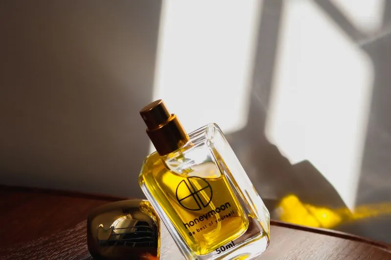 Bottle of golden perfume on a wooden tray, caught in a shaft of sunlight