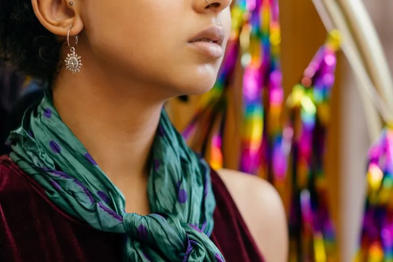 Green scarf with purple polka dots knotted at the neck of a woman in a burgundy velvet top
