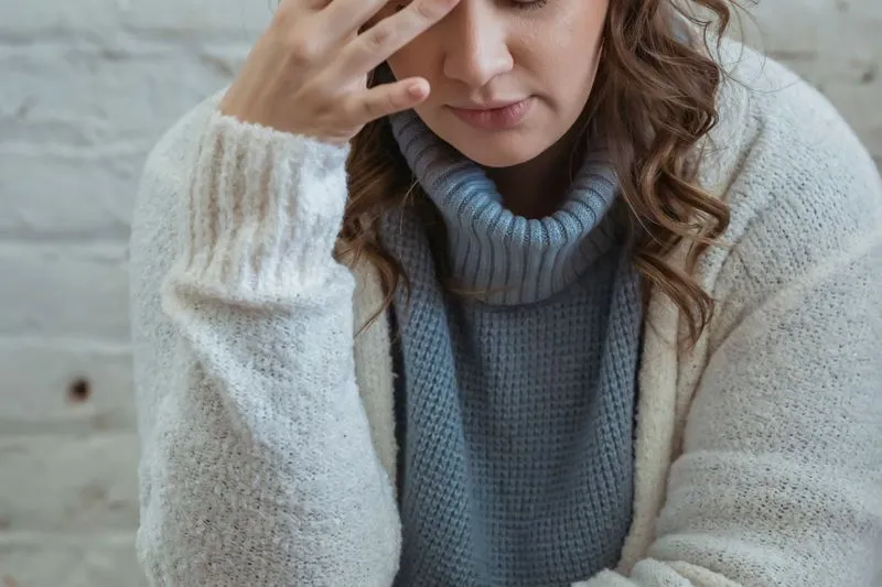 Woman with her head bowed and a hand on her forehead, taking a moment to breathe
