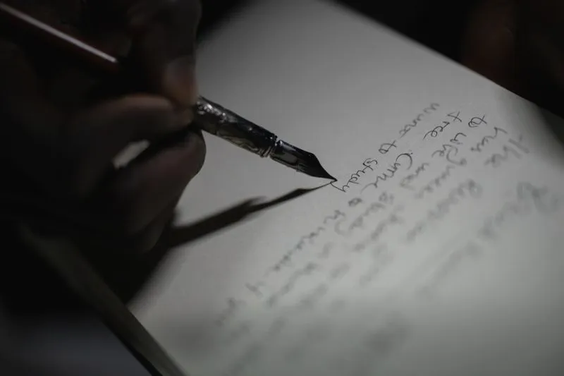 Close-up of a hand writing a few lines with a fountain pen on a blank page