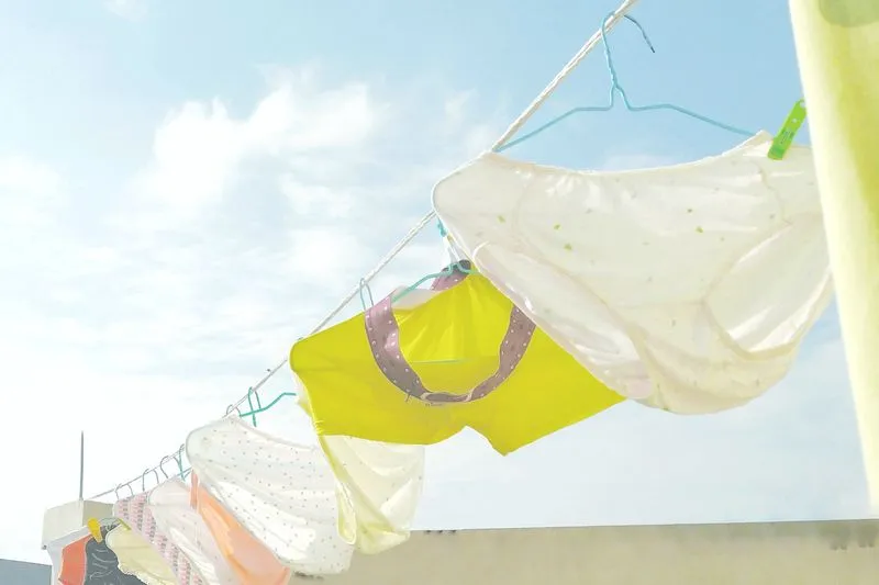 White, yellow and pink cotton knickers hanging from a washing line under a blue sky