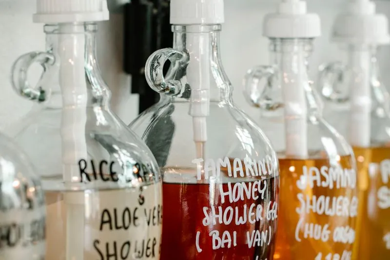 Glass pump dispensers of honey, jasmine and aloe vera shower gel with handwritten labels