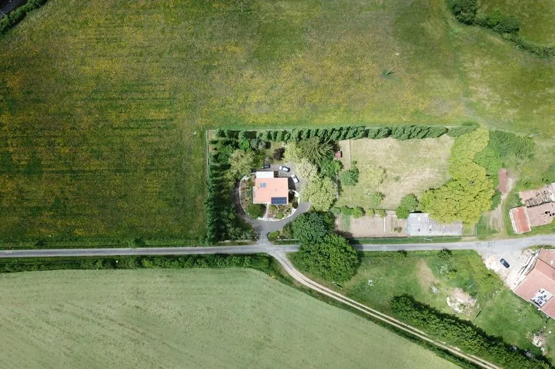 Aerial view of a country house with a hedged garden, surrounded by fields