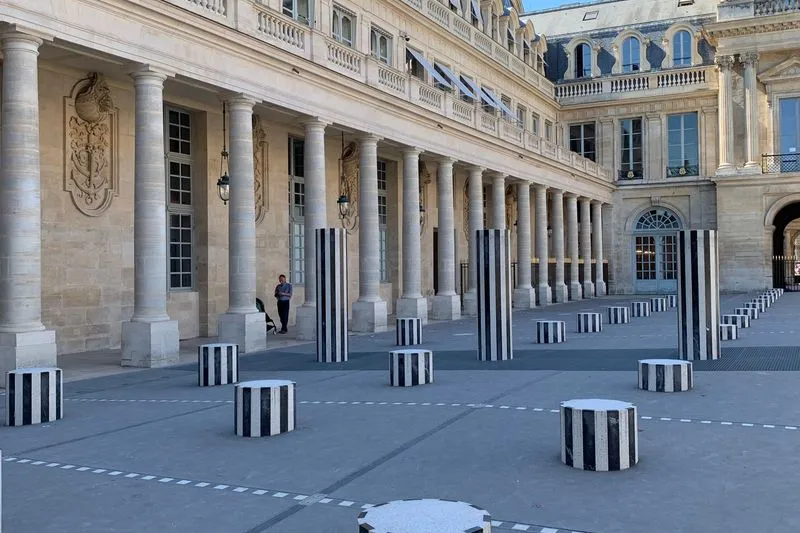Black-and-white striped columns of different heights in the courtyard of the Palais-Royal, in front of a stone colonnade