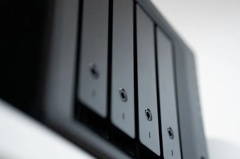Front of a black four-bay NAS seen at an angle, its drive trays lined up