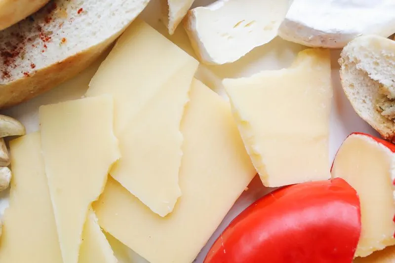 Close-up of an assortment of sliced cheeses with a few pieces of bread