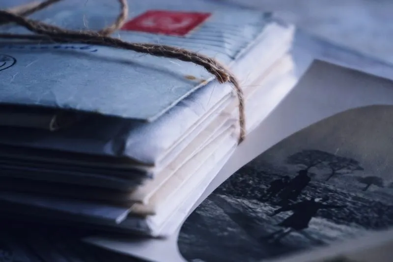 A stack of old envelopes tied with twine, beside an old black-and-white photograph