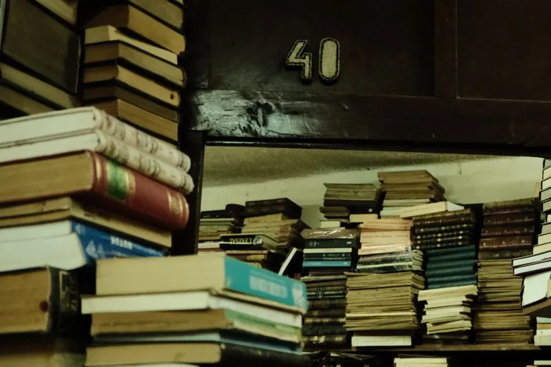 Stacks of old books with worn covers on shelves